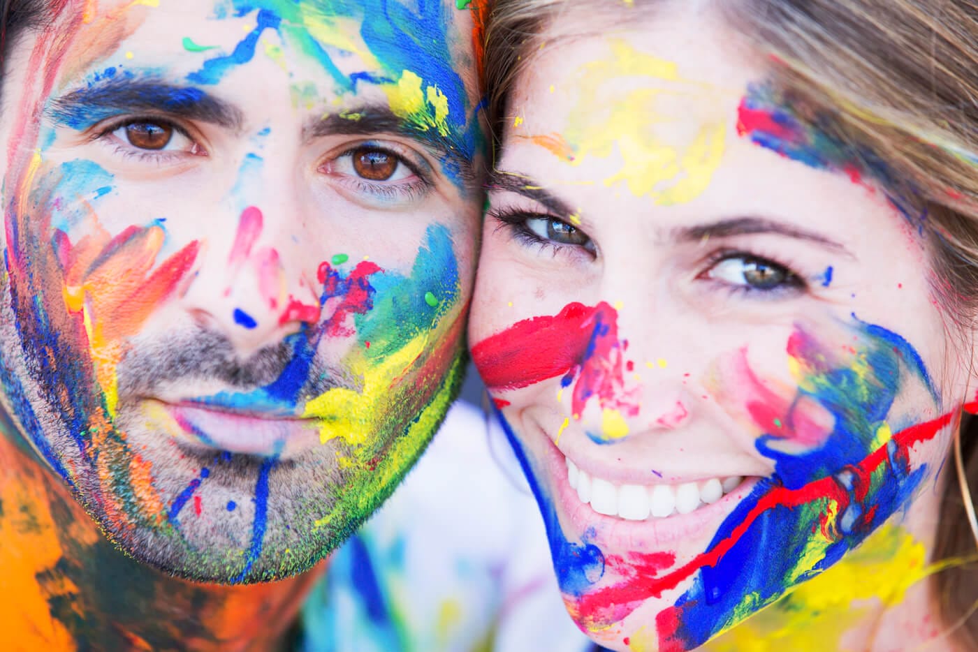 Playful NYC Engagement Photo of a couple using colorful face paint to creatively personalize their gallery.