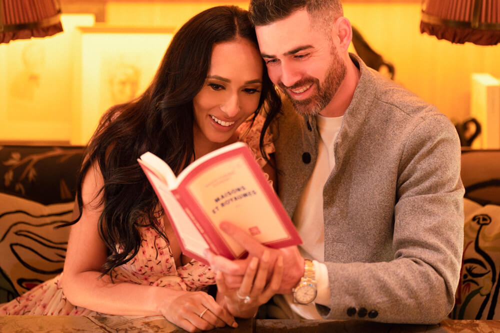 Engaged couple romantically reading a book together in a cozy cafe during their NYC engagement photography session.