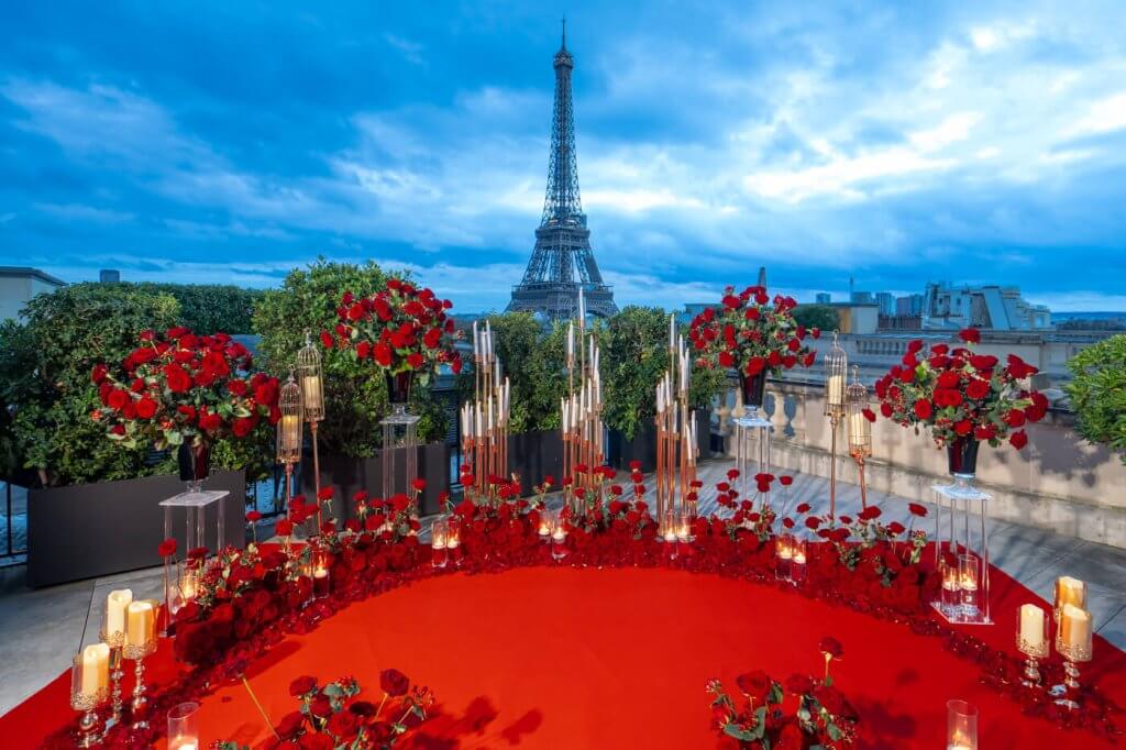 Surprise Proposal Photographer captures a luxurious proposal scene with thousands of red rose petals and the Eiffel Tower against a vivid blue sky