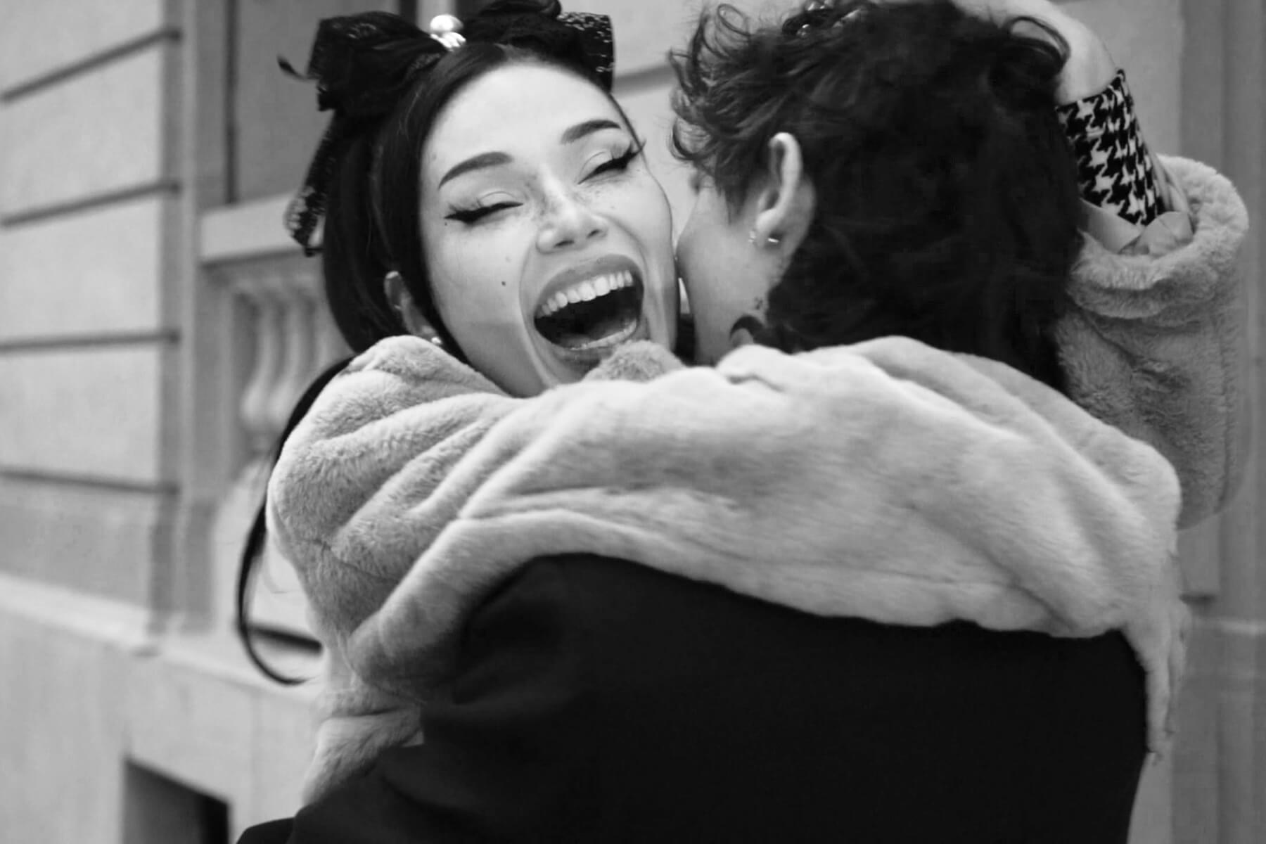 A candid black-and-white photo beautifully captures a woman joyfully embracing her partner in a burst of happiness, moments after his romantic marriage proposal.
