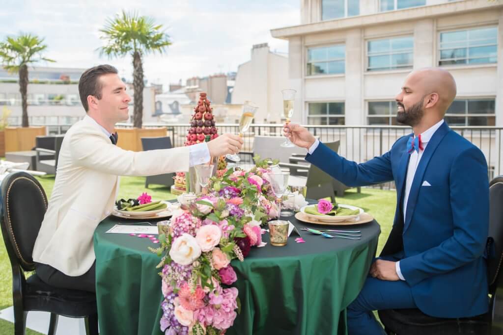 Stylish gentlemen toasting to love at a fabulously decorated table moments after their same-sex proposal engagement